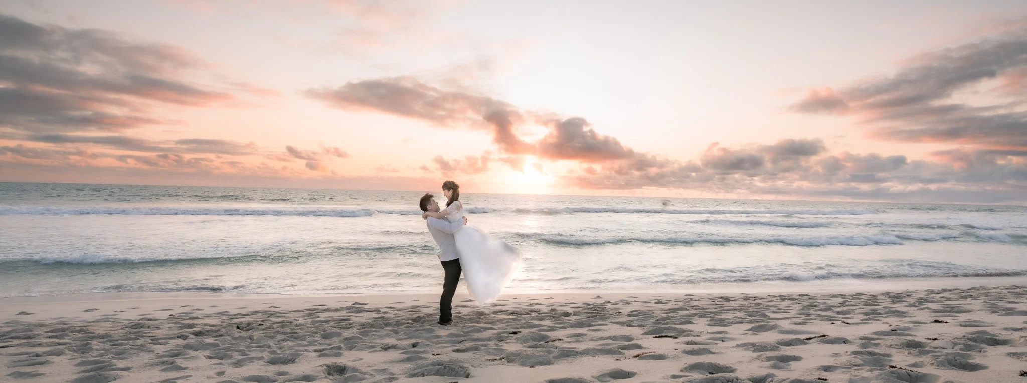 Angle and Andrew sharing a playful lift at sunset on Burns Beach, Perth, Western Australia