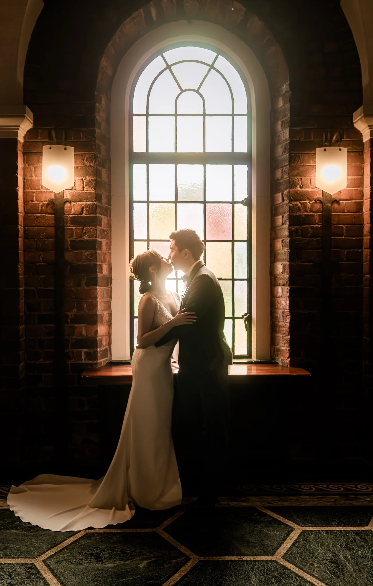 Melody and Ken sharing a kiss beneath a stained glass window at UWA in Perth, Western Australia