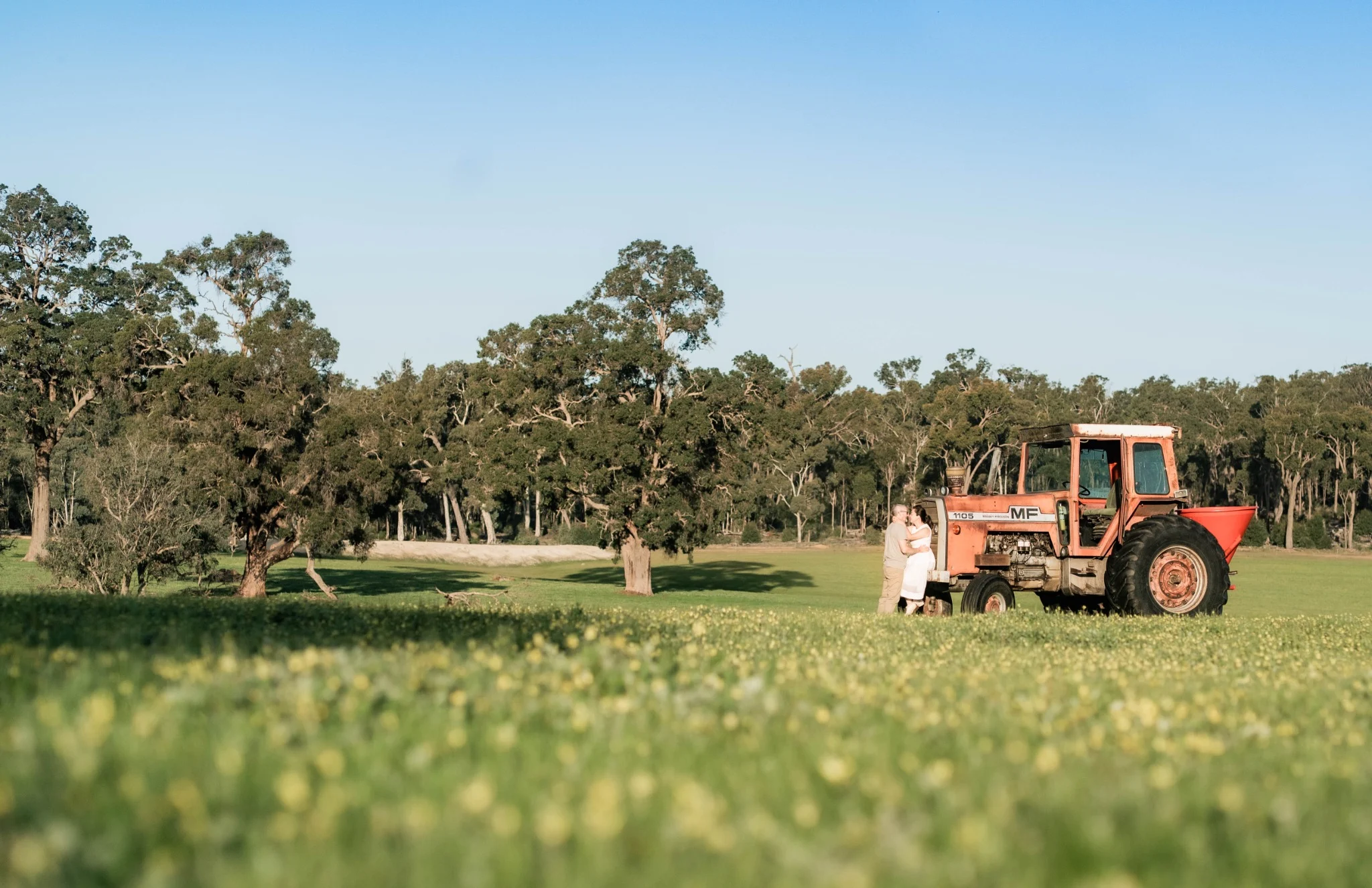 Tammy and her partner beside a tractor on a farm near Perth, Western Australia